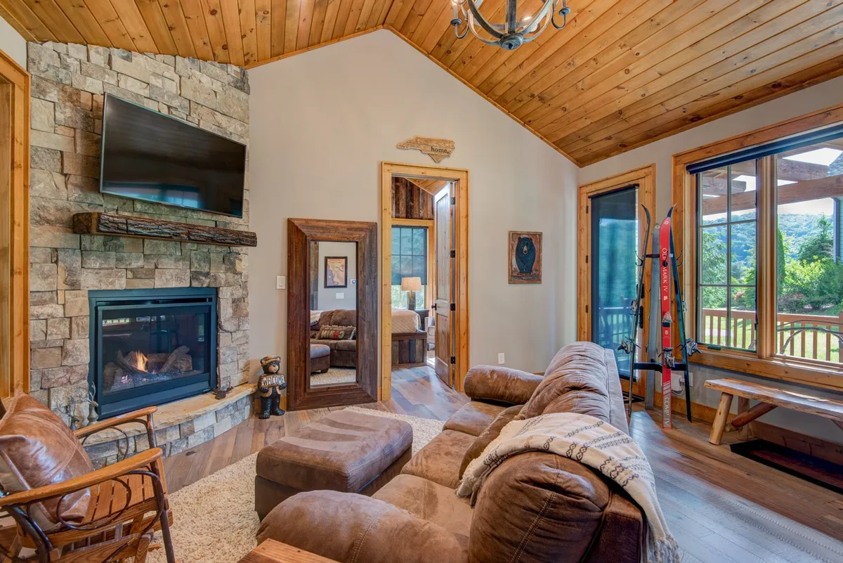 A cozy living area centered around a welcoming fireplace, with large windows framing scenic views. Comfortable seating invites guests to unwind, while the decorative mirror and soft lighting create a warm, romantic atmosphere.