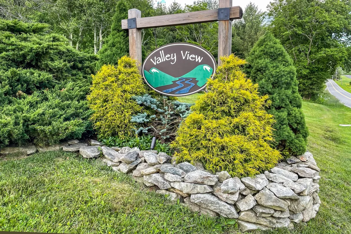 An exterior shot featuring a 'Valley View' sign with landscaped greenery and a stone border, set against a backdrop of natural beauty. The image hints at local exploration opportunities and the pristine environment awaiting guests.
