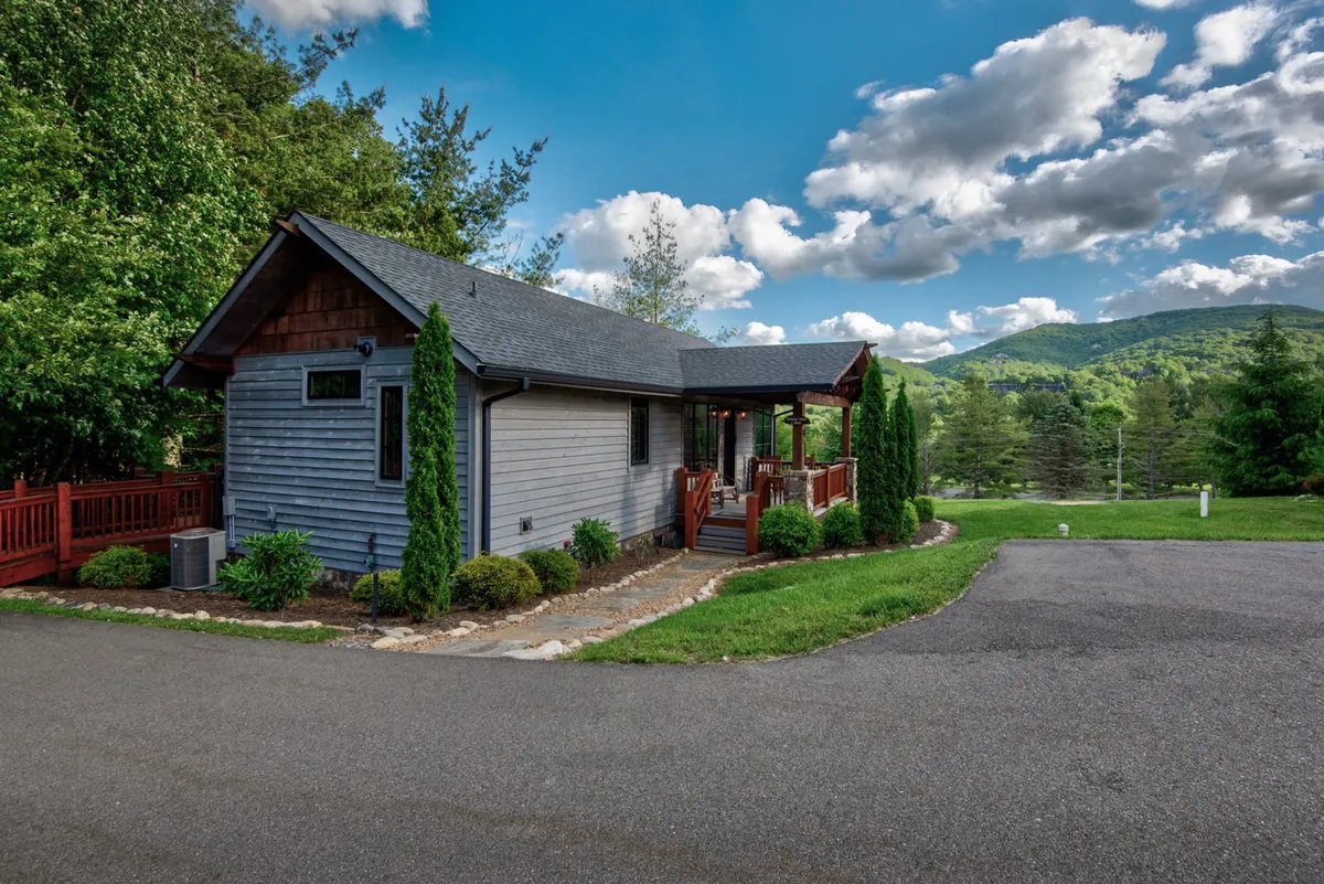 A wide exterior view of the house and its porch, surrounded by vibrant greenery. The scene is tranquil and inviting, encouraging exploration of the natural landscape just steps from the door.
